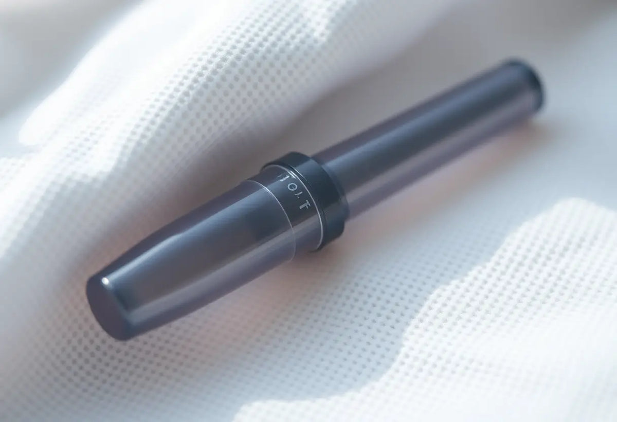 Photo centrale : petit cylindre plastique flexible sur tissu blanc, similaire à l'implant contraceptif