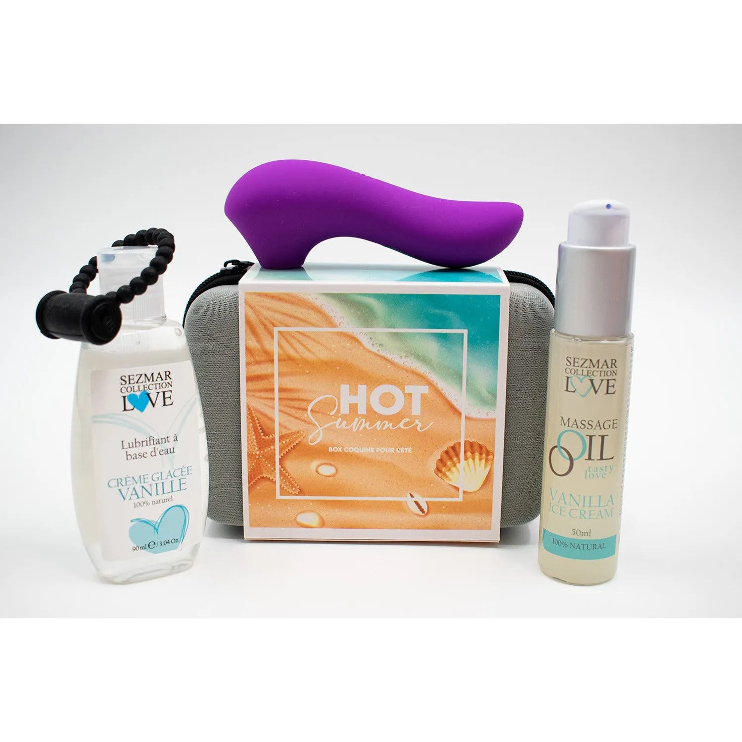 Coffret estival Box Hot Summer avec lubrifiant vanille, huile de massage et stimulateur violet, fond plage.