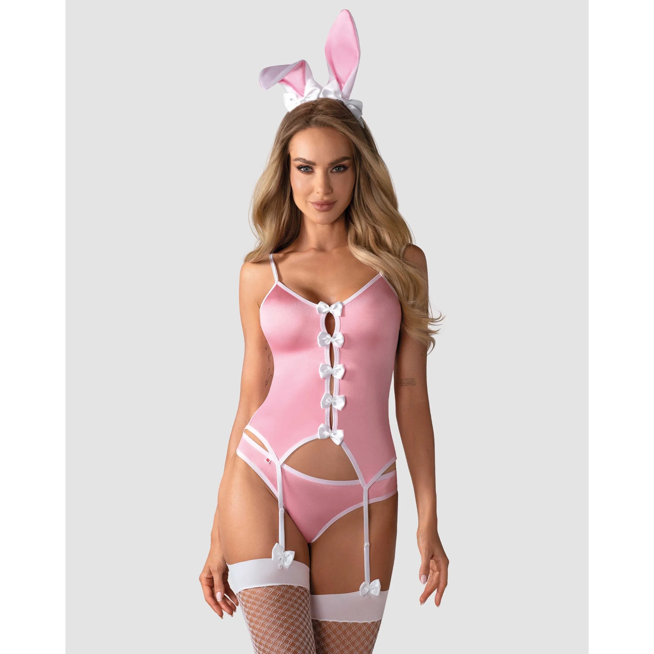 Costume lapin rose avec bretelles, jarretières, oreilles et nœuds blancs, mettant en valeur la poitrine et la taille.