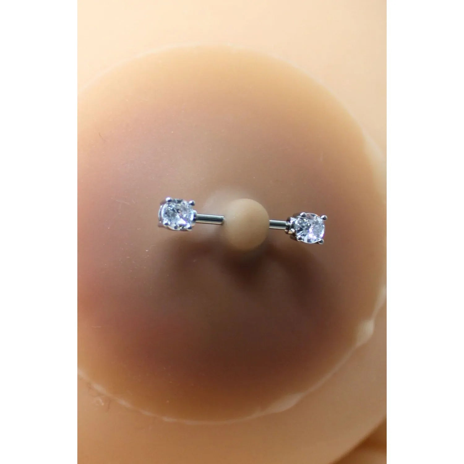 Cache-tétons silicone peau métissée avec piercing faux diamant, design élégant et discret pour allure raffinée.