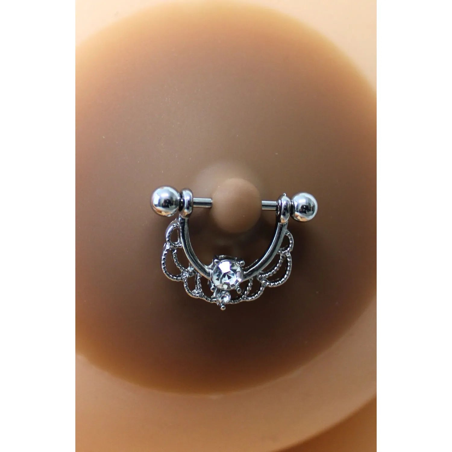 Cache-tétons silicone marron avec piercing barre argenté et faux diamant, conçu pour peaux foncées, élégant et réutilisable.