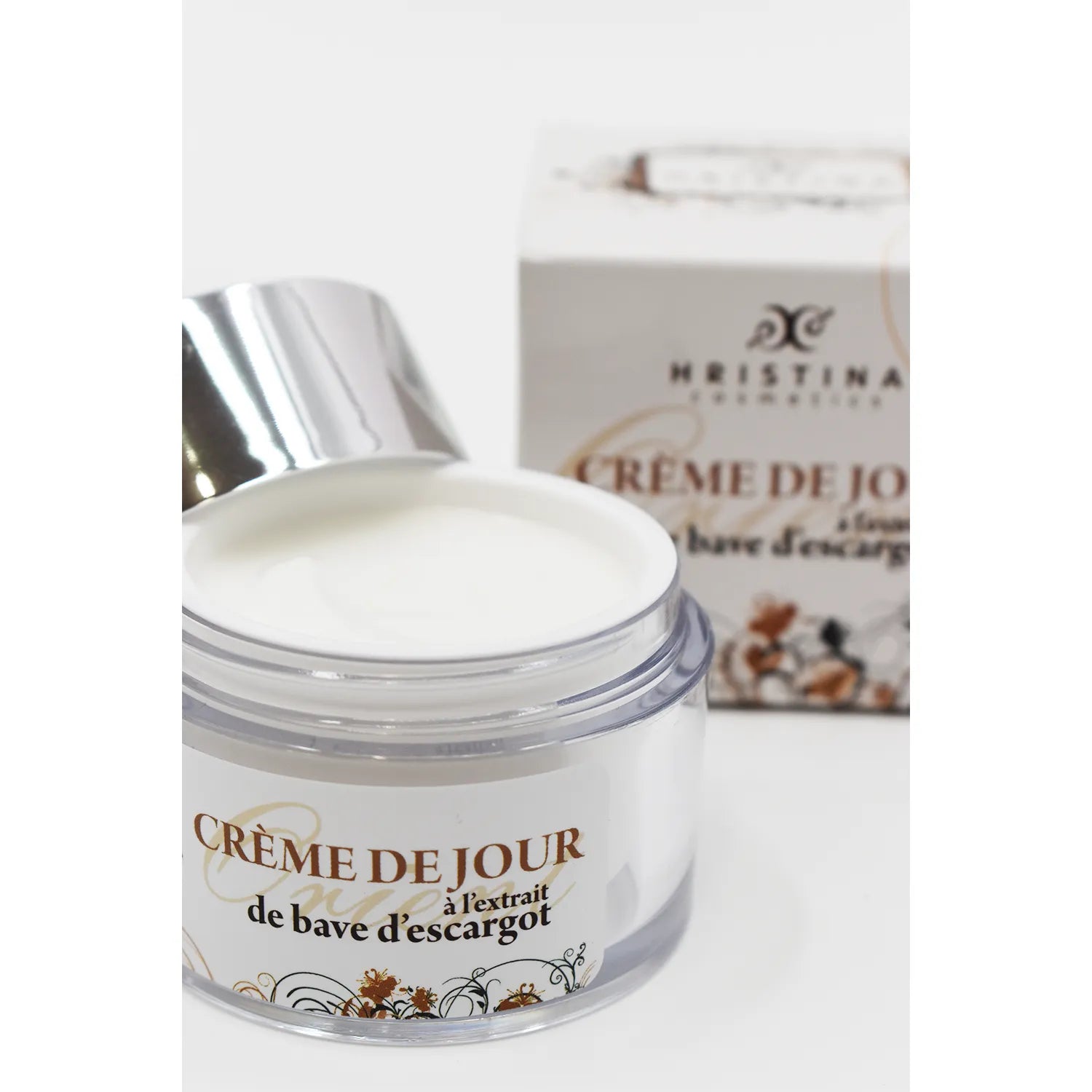 Crème de jour à la bave d'escargot, pot blanc avec couvercle argenté, boîte en arrière-plan, soin anti-âge hydratant.
