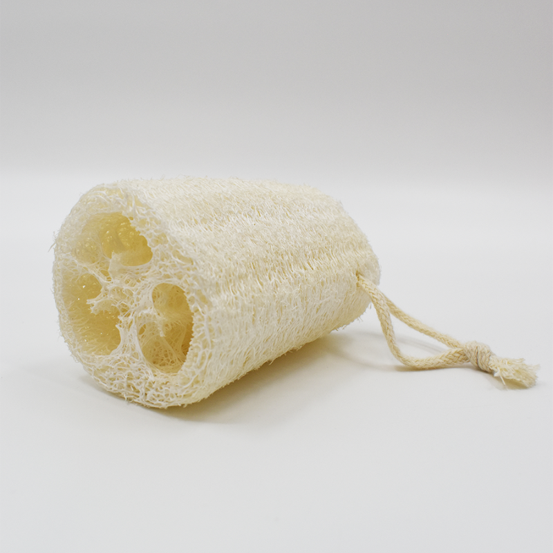 Éponge luffa naturelle beige, cylindrique, avec fibres visibles et cordelette, idéale pour exfoliation douce et écologique.