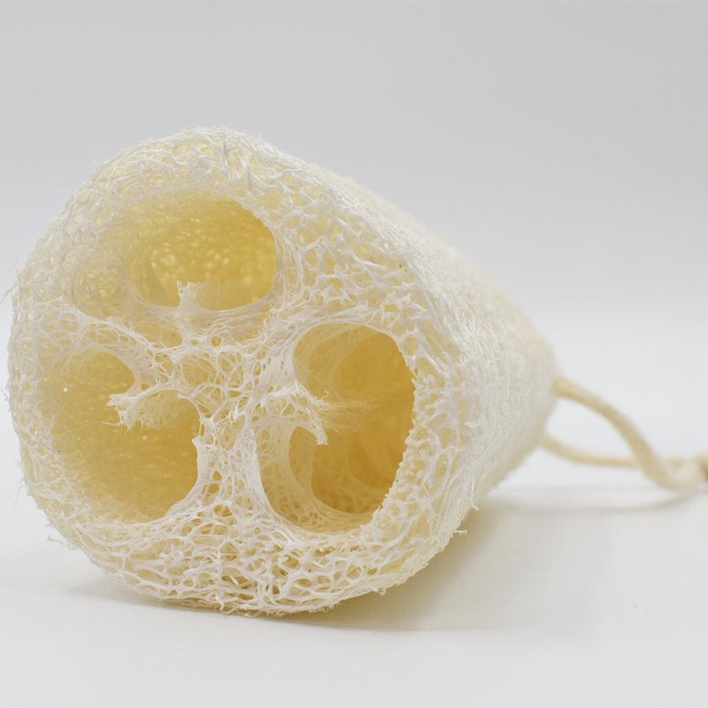 Éponge luffa naturelle beige, cylindrique, fibres végétales apparentes, idéale pour exfoliation douce et écologique.