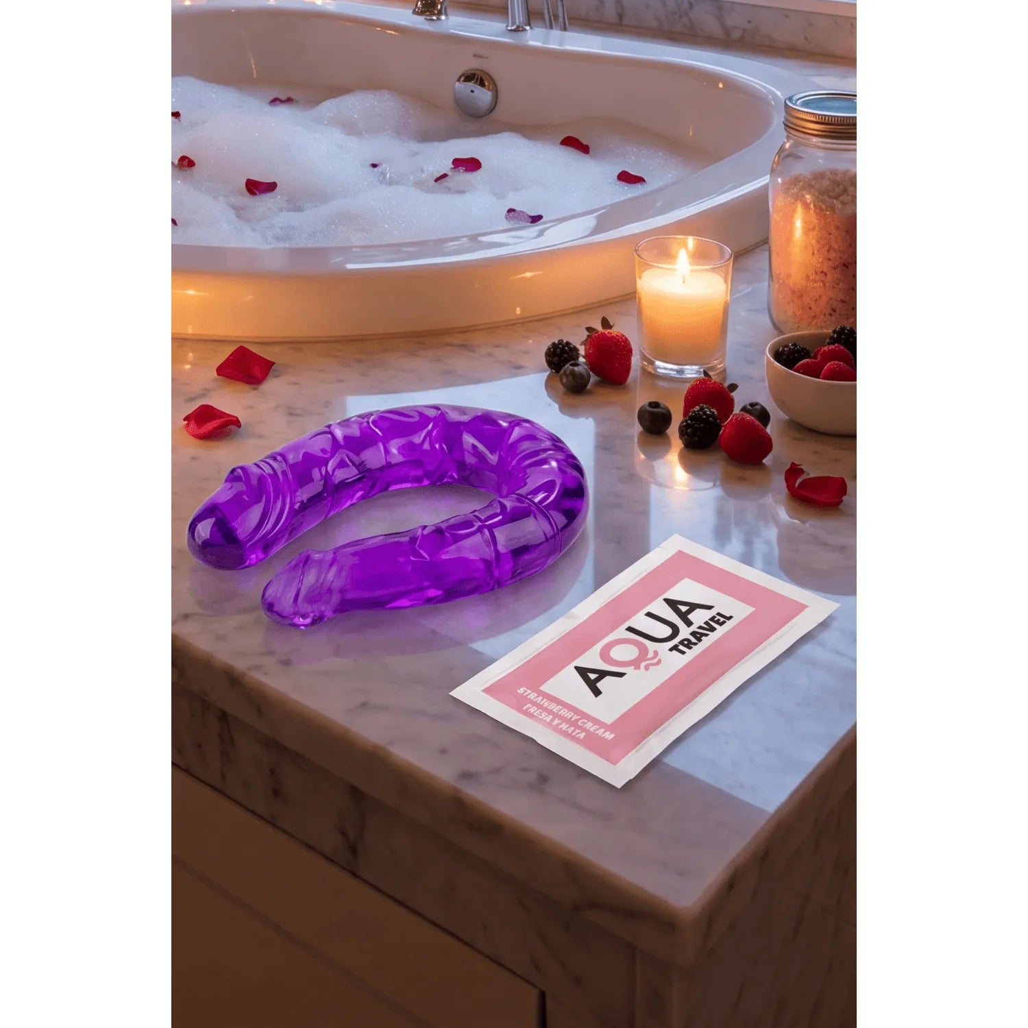 Double dong violet flexible avec reliefs, posé près d'une dosette de lubrifiant sur un rebord de baignoire.