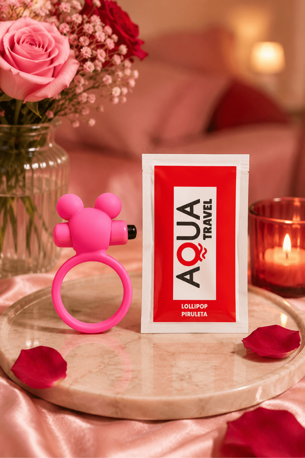 Anneau vibrant ourson rose avec oreilles rondes et dosette de lubrifiant sur plateau, ambiance romantique.