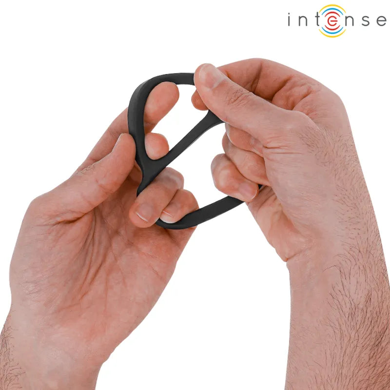 Anneau double en silicone noir ergonomique, design doux et ajustable, tenu par une main pour améliorer l'expérience intime.