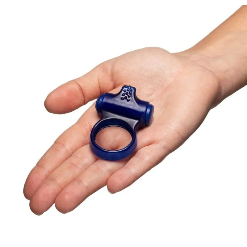 Anneau vibrant bleu en silicone avec tête stimulante et pointes surélevées, tenu dans une main pour une expérience intime.