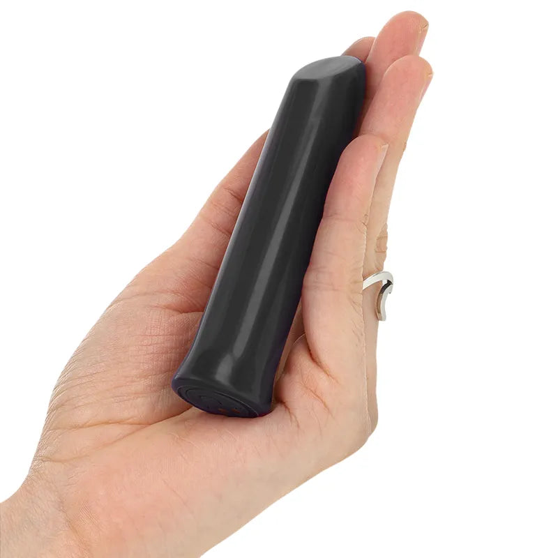 Balle vibrante violette en silicone étanche, compacte et douce, tenue dans une main pour démontrer sa taille portable.