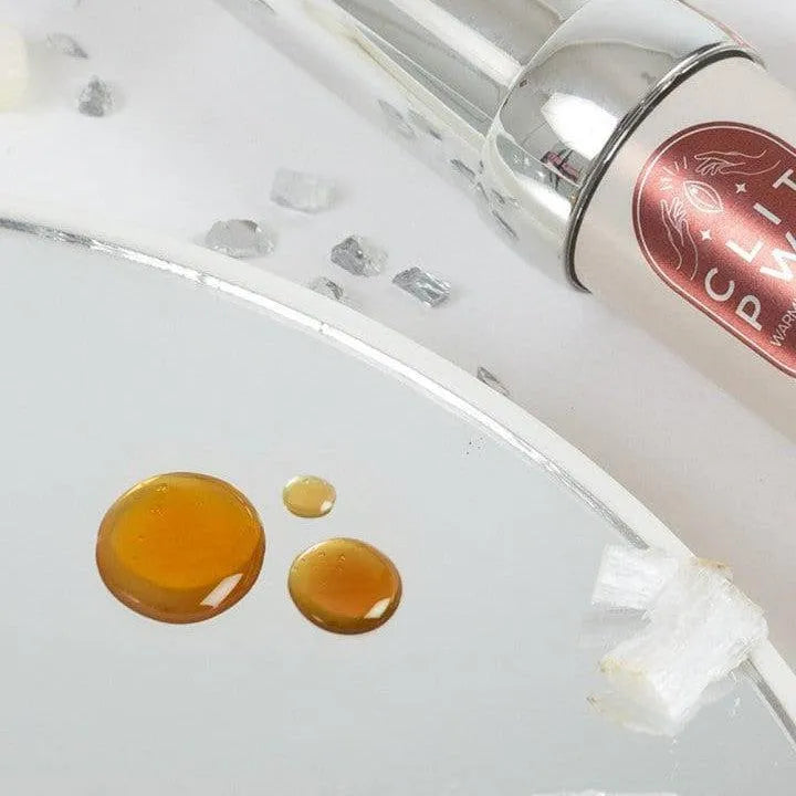 Baume chauffant clitoris menthe chocolat, tube élégant argenté, texture fluide ambrée, expérience sensorielle unique.
