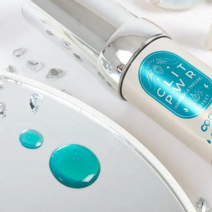 Baume stimulant clitoris noix de coco, flacon blanc avec bouchon argenté, étiquette turquoise, sur fond clair.
