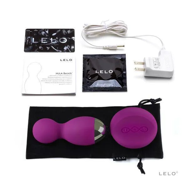 Boules vibrantes télécommandées en silicone violet avec accessoires, câble de charge et manuel sur fond blanc.