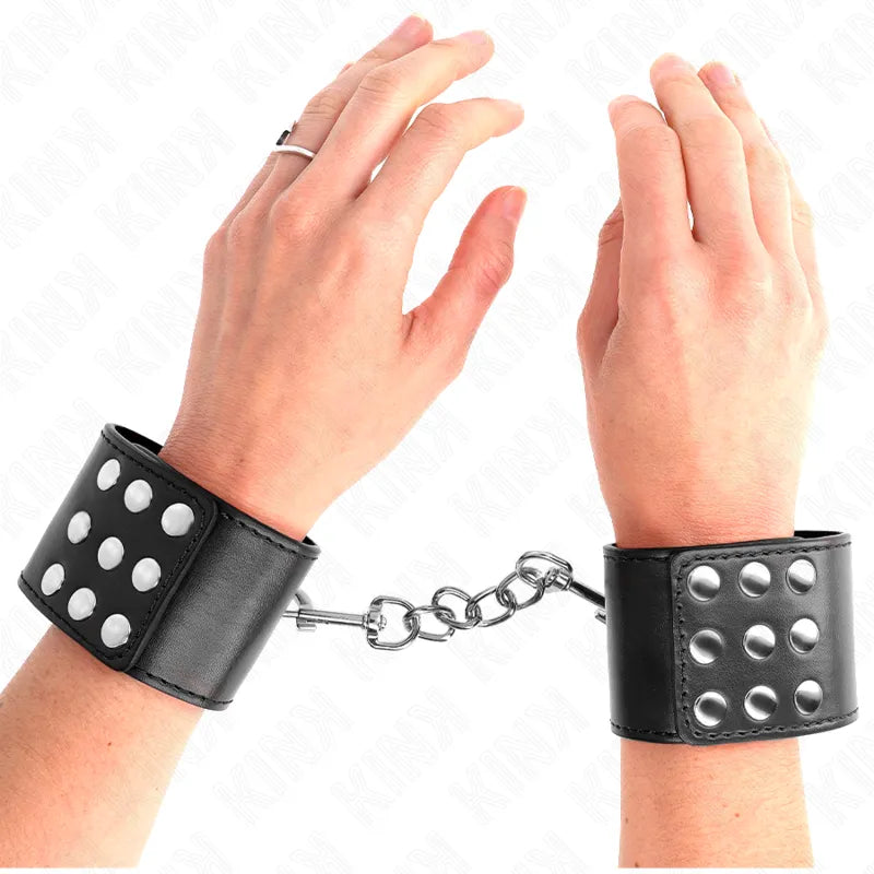 Bracelets BDSM en cuir noir avec rivets métalliques, chaîne centrale, élégance et résistance pour séances spécialisées.