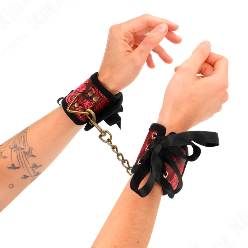 Bracelets BDSM en cuir rouge et noir, ornés de motifs, avec chaîne dorée, pour sessions élégantes et robustes.