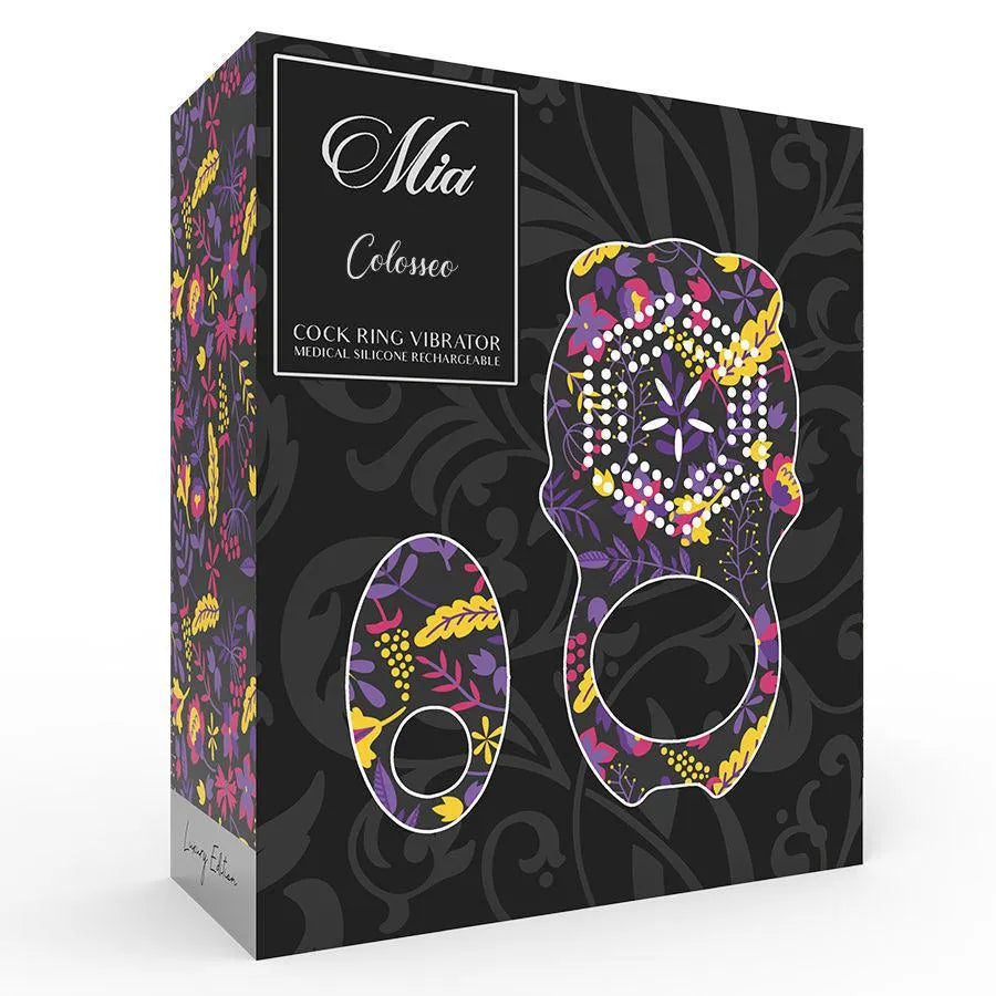 Anneau vibrant en silicone médical noir avec motifs colorés, télécommande incluse, sur fond floral élégant.