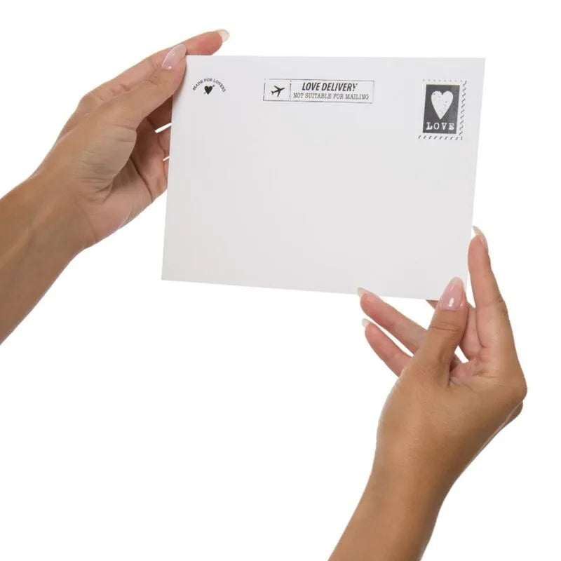 Femme tenant une enveloppe blanche avec timbres Love, liée au Coffret Cadeau Érotique Huiles Et Positions Kamasutra.