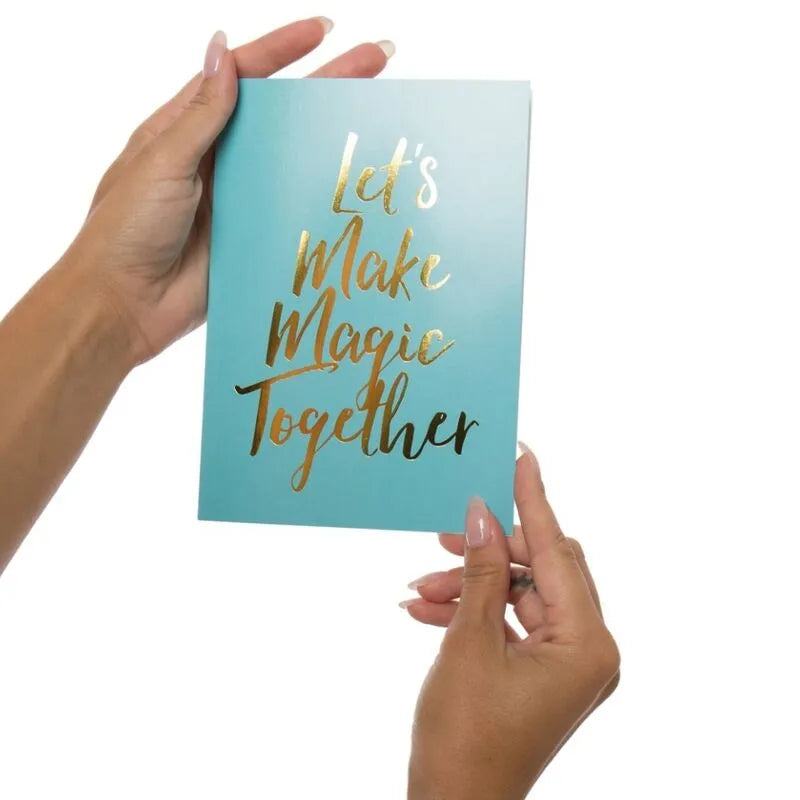 Coffret cadeau érotique bleu avec texte doré Let's Make Magic Together, tenu par des mains, pour exploration sensuelle.