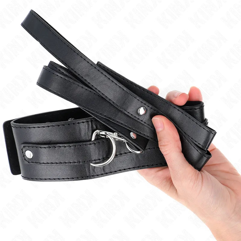 Collier BDSM en cuir noir élégant, réglable, avec boucle métallique, tenu dans une main.