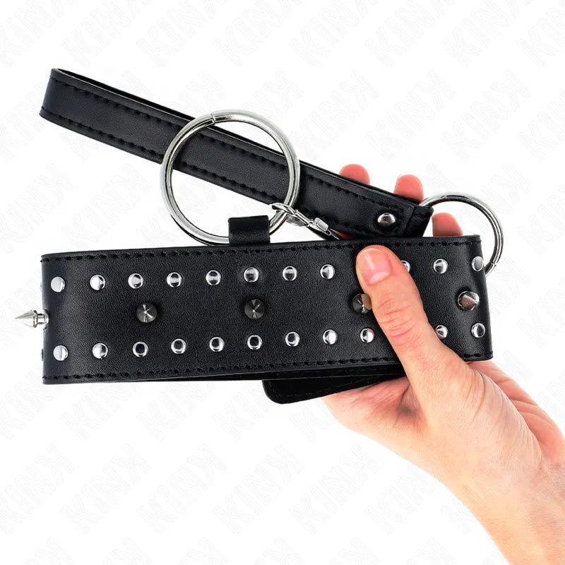 Collier BDSM en cuir végétalien noir avec rivets métalliques, design élégant et durable, tenu en main.