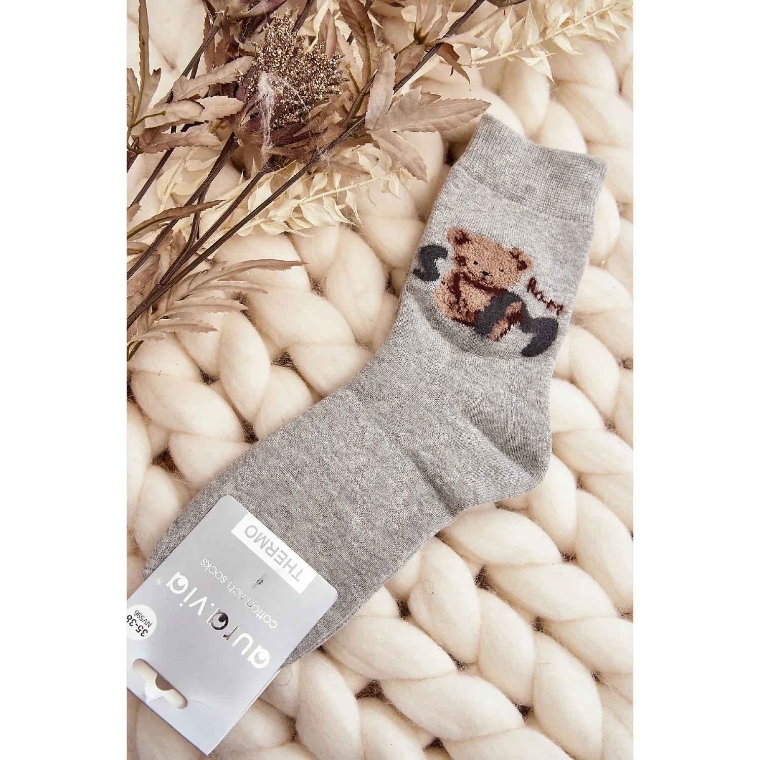 Chaussettes grises en coton avec patch ourson, trépointe ajustée, sur fond de laine blanche, idéales pour temps froid.