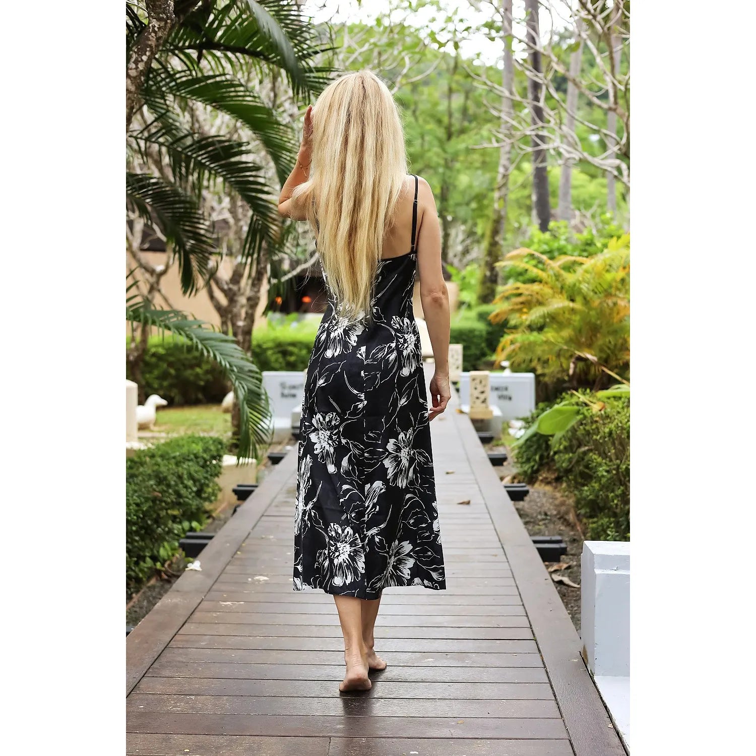 Chemise de nuit longue en satin noir à motifs floraux, élégante et exotique, portée dans un jardin tropical.