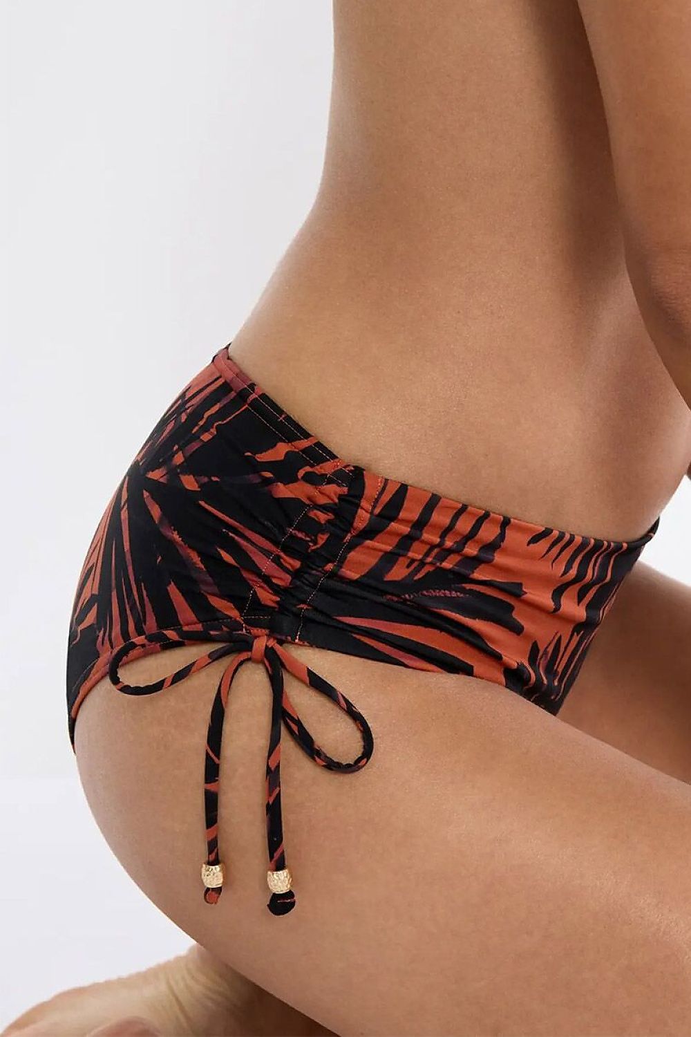 Culotte bikini Triumph Summer Palm, motif tropical noir et orange, côtés réglables avec détails métalliques élégants.