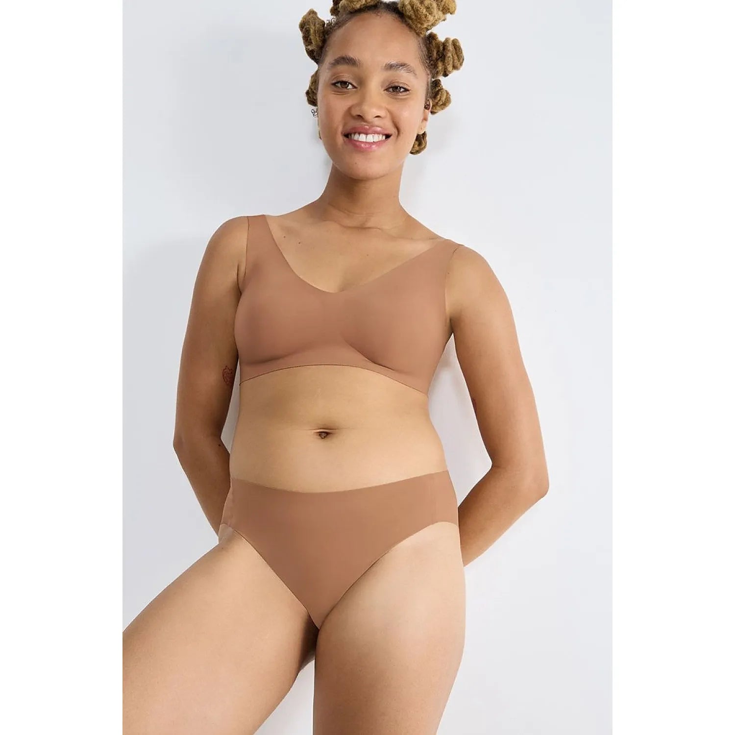 Femme portant culottes invisibles Sloggi marron, sans couture, en polyamide recyclé, confort et invisibilité assurés.