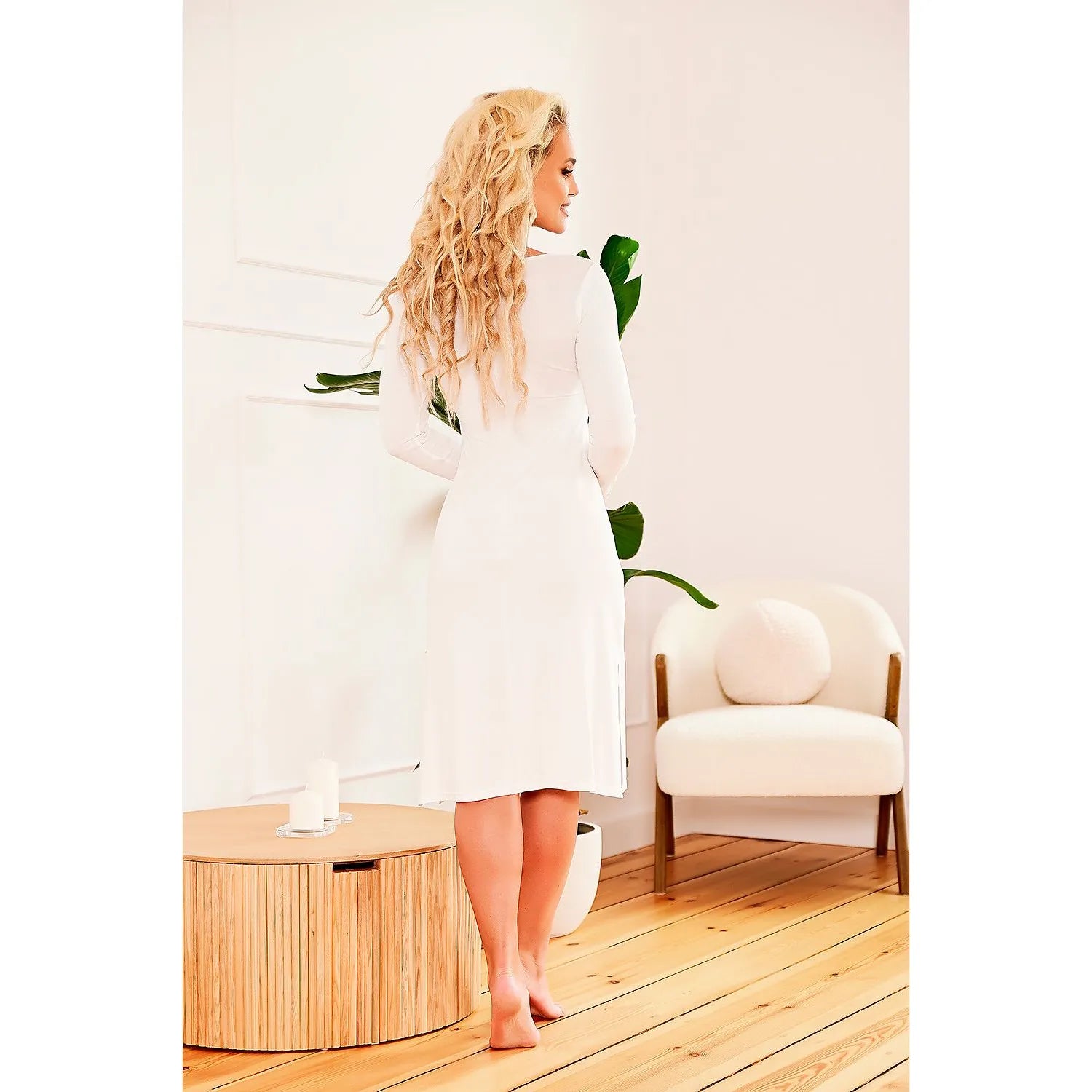 Chemise de nuit blanche 3/4 en viscose avec dentelle aux poignets, fentes latérales, présentée dans un intérieur moderne.