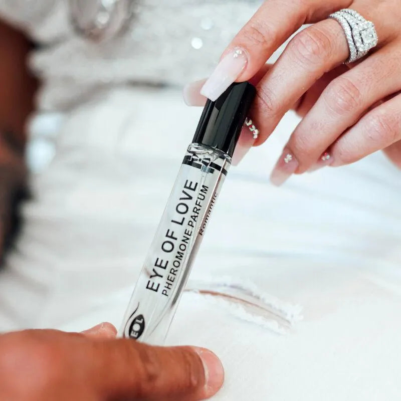 Flacon élégant d'Eau De Cologne Phéromone Romantique Pour Homme, transparent avec bouchon noir, tenu par une main.