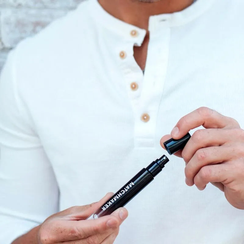 Flacon noir d'Eau De Cologne Phéromones Séduisante pour femmes, élégant et moderne, tenu par une main masculine.