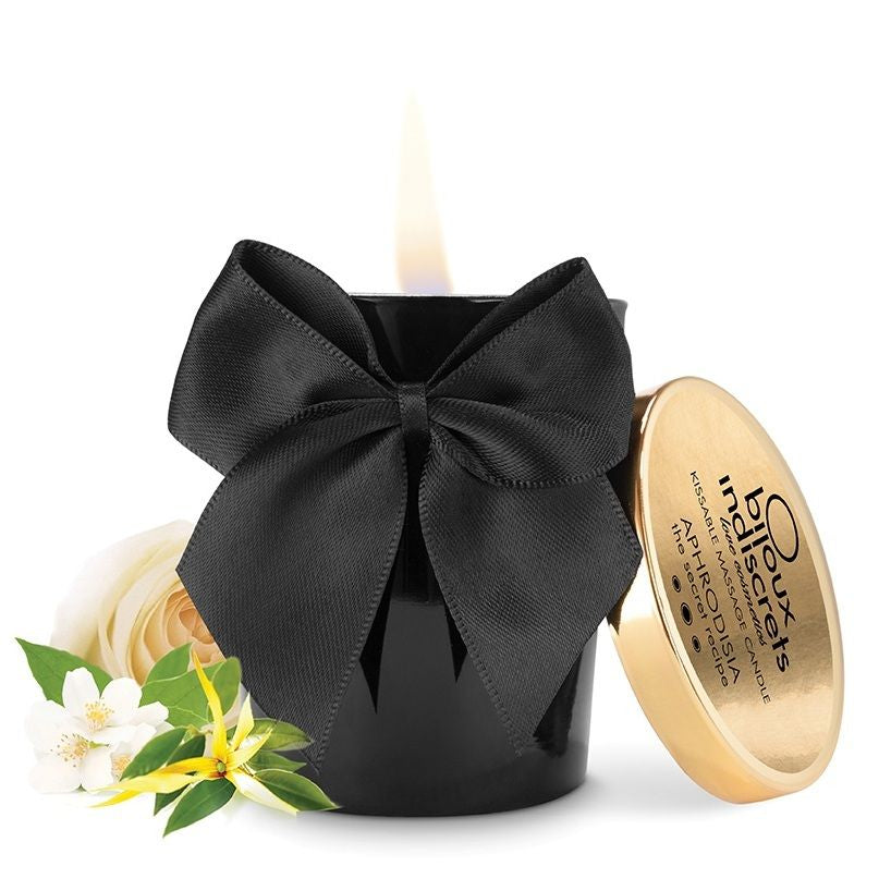 Bougie noire avec flamme, couvercle doré, ruban noir, fleurs blanches; bougie de massage parfumée Aphrodisia.