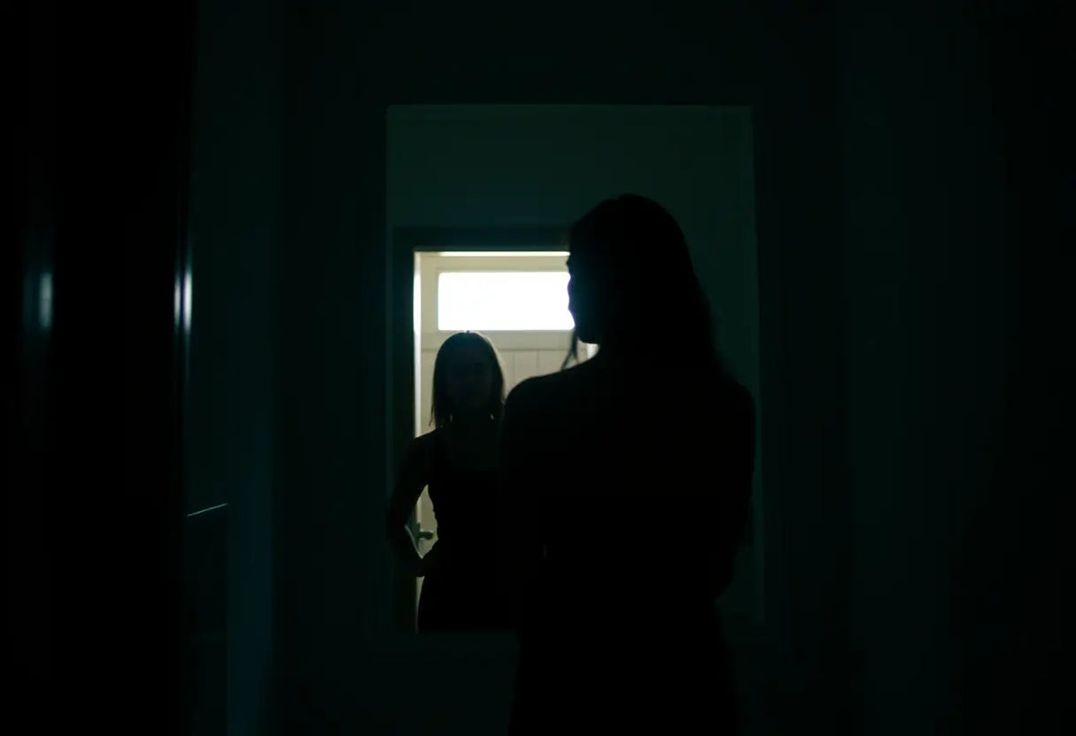 Un silhouette féminine devant un miroir dans une salle de bains