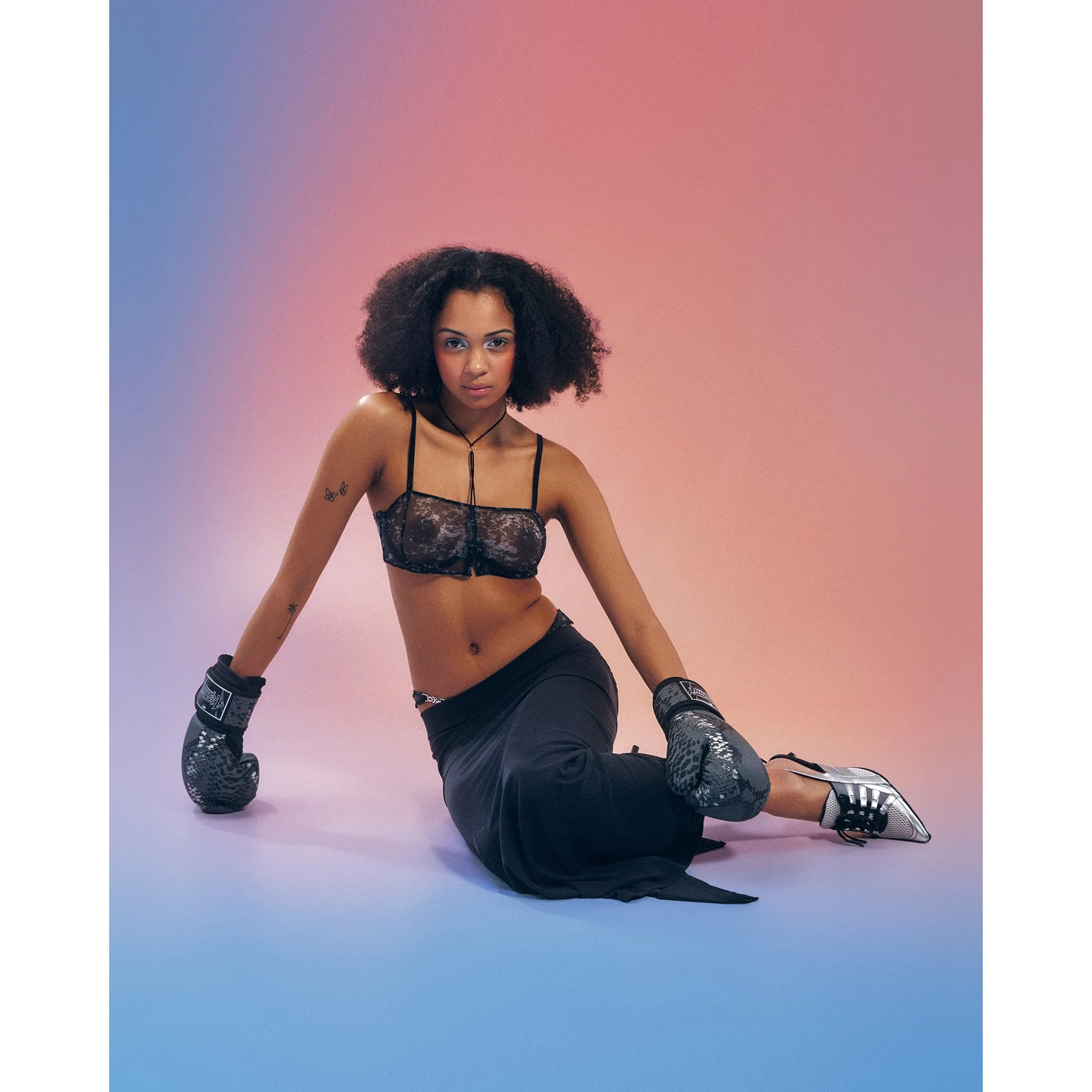 Soutien-gorge Corrosis noir transparent, froncé, armatures réglables, motif unique, porté par modèle sur fond dégradé.
