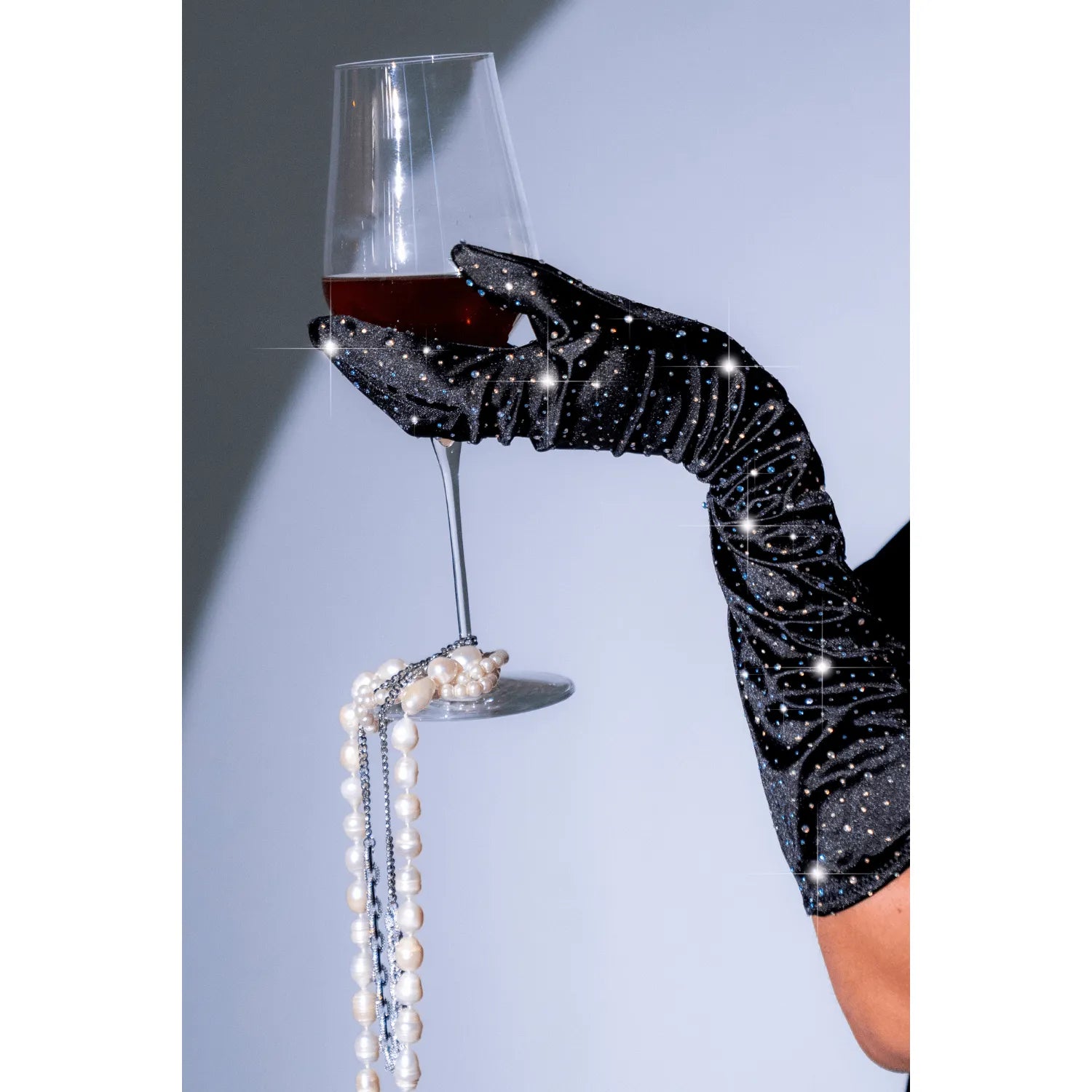 Gants opéra satin noir extensible avec strass, tenant un verre de vin, élégance et glamour pour soirées Mapalé.