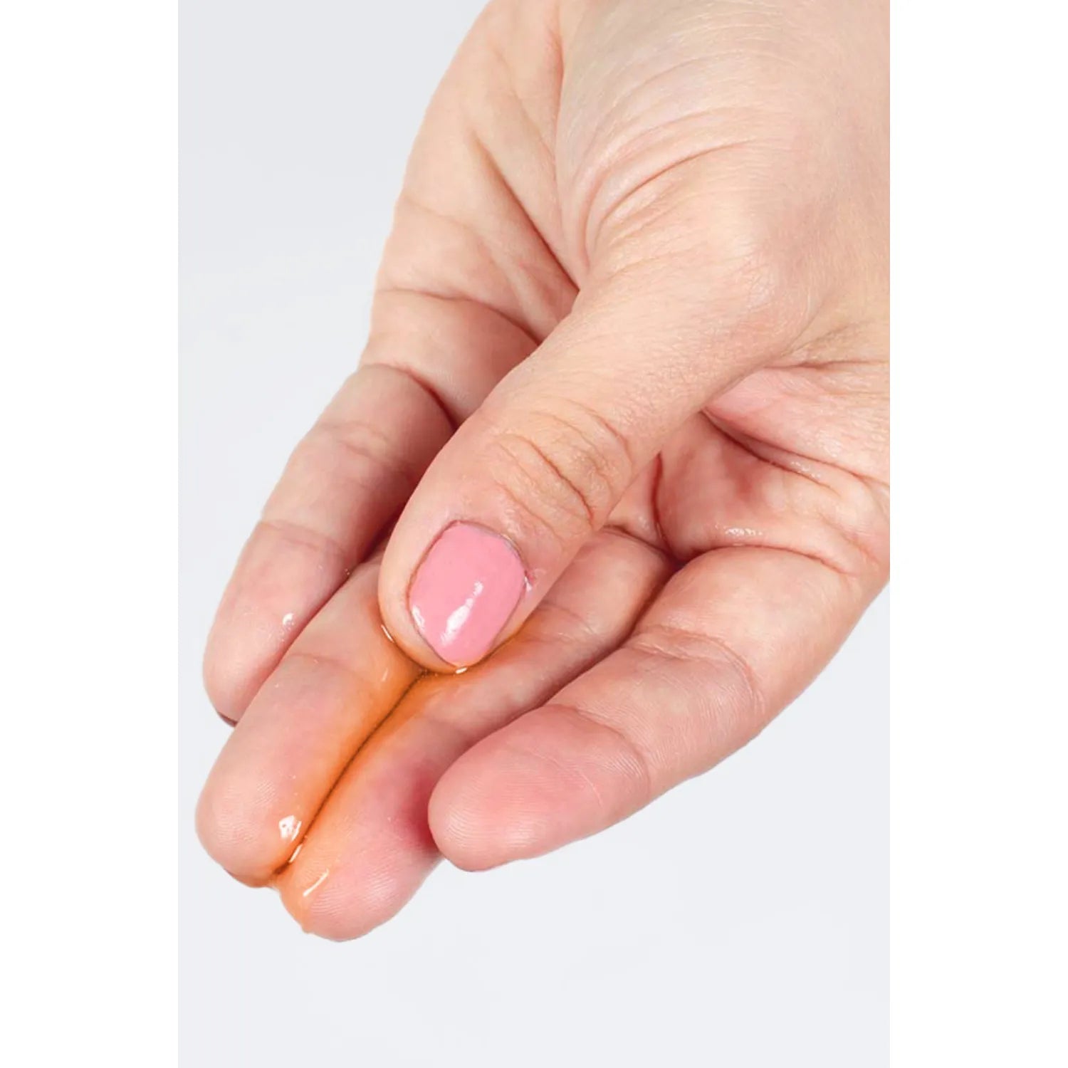 Huile de massage lubrifiante fruit de la passion, texture fluide et chauffante, main appliquant le produit.