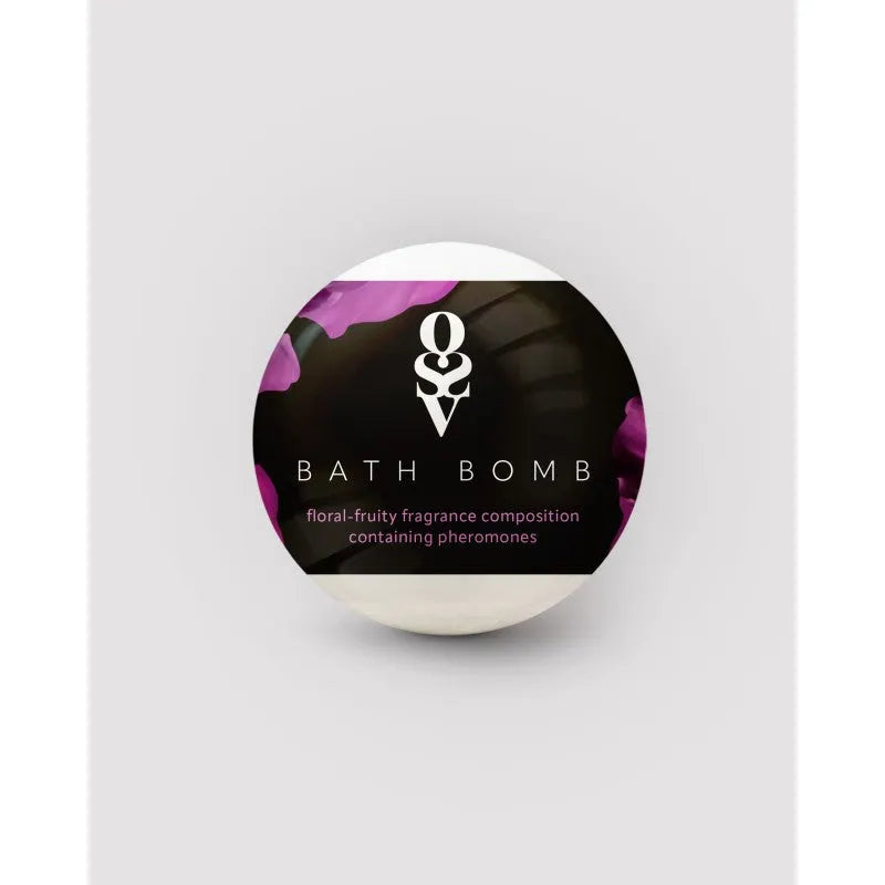 Bombe de bain ronde 100g, emballage noir avec motifs floraux violets, parfum floral fruité gourmand aux phéromones.