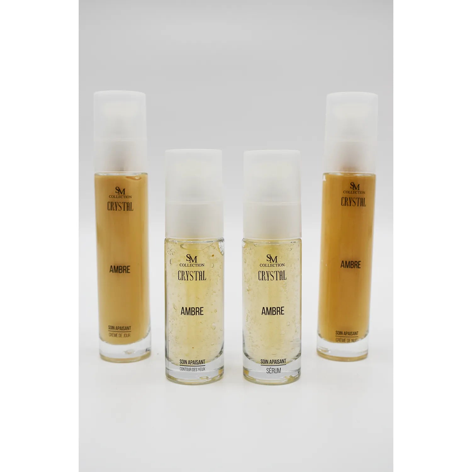 Flacons de soins apaisants à l'ambre, gamme complète pour peaux sensibles, crème contour des yeux et sérum.
