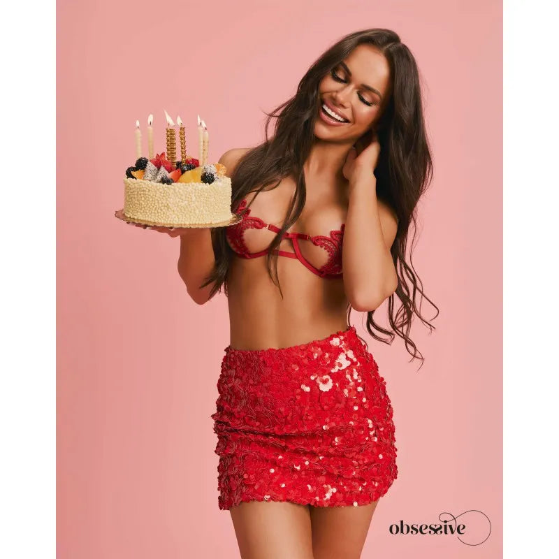 Ensemble lingerie rouge dentelle avec soutien-gorge à armatures et string ouvert, porté par un modèle souriant.