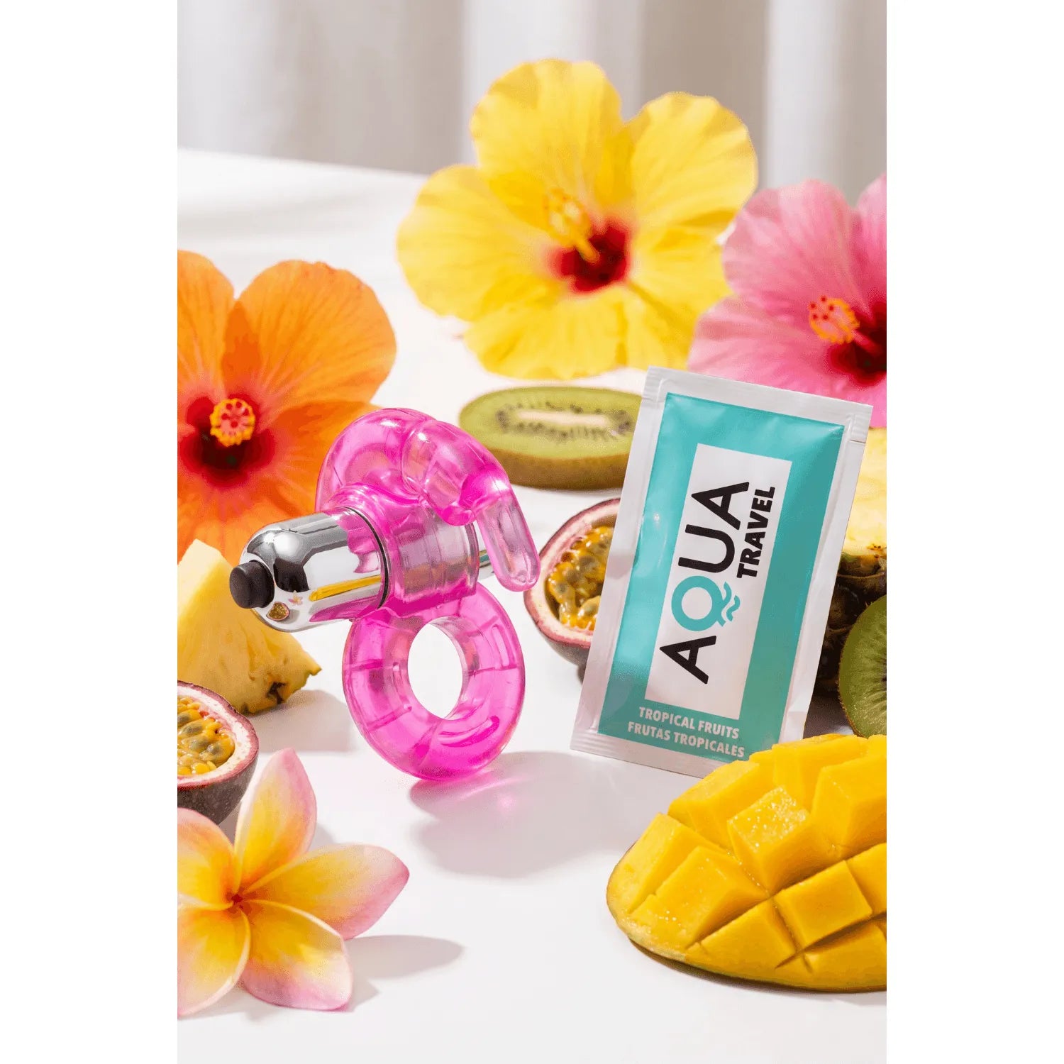 Anneau vibrant rose double stimulation lapin, hyper extensible, sur fond de fleurs et fruits tropicaux.