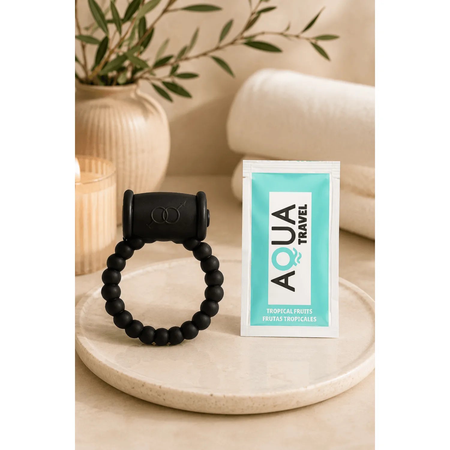 Cockring vibrant noir mat perlé avec bullet amovible, posé sur une surface beige, à côté d'un sachet Aqua Travel.