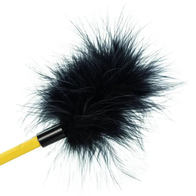 Accessoire BDSM plume noire fausse fourrure, manche jaune, outil de séduction sensuelle et raffinée.