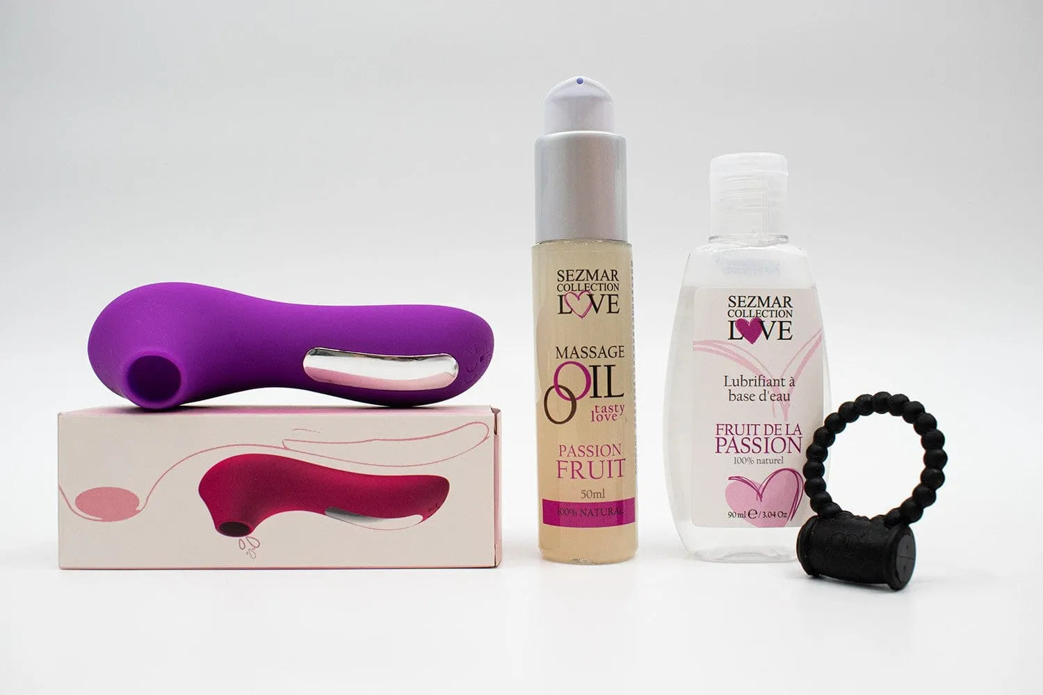 Box Couple Été avec stimulateur violet, anneau noir, huile de massage fruit de la passion, ambiance exotique.