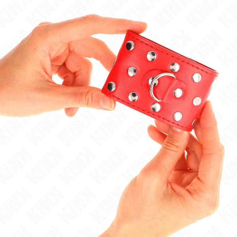 Bracelet BDSM en cuir rouge avec rivets métalliques, anneau central, design élégant et robuste pour séances sécurisées.