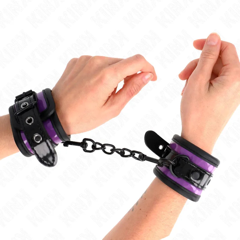 Bracelets BDSM en cuir végétalien noir et violet, ajustables, avec chaîne de connexion, portés sur poignets.