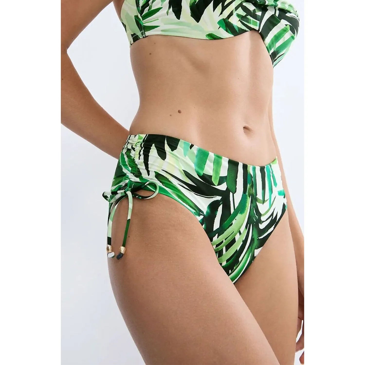Culotte bikini verte à imprimé palmier, détails métalliques, côtés réglables, coupe taille moyenne, style moderne.