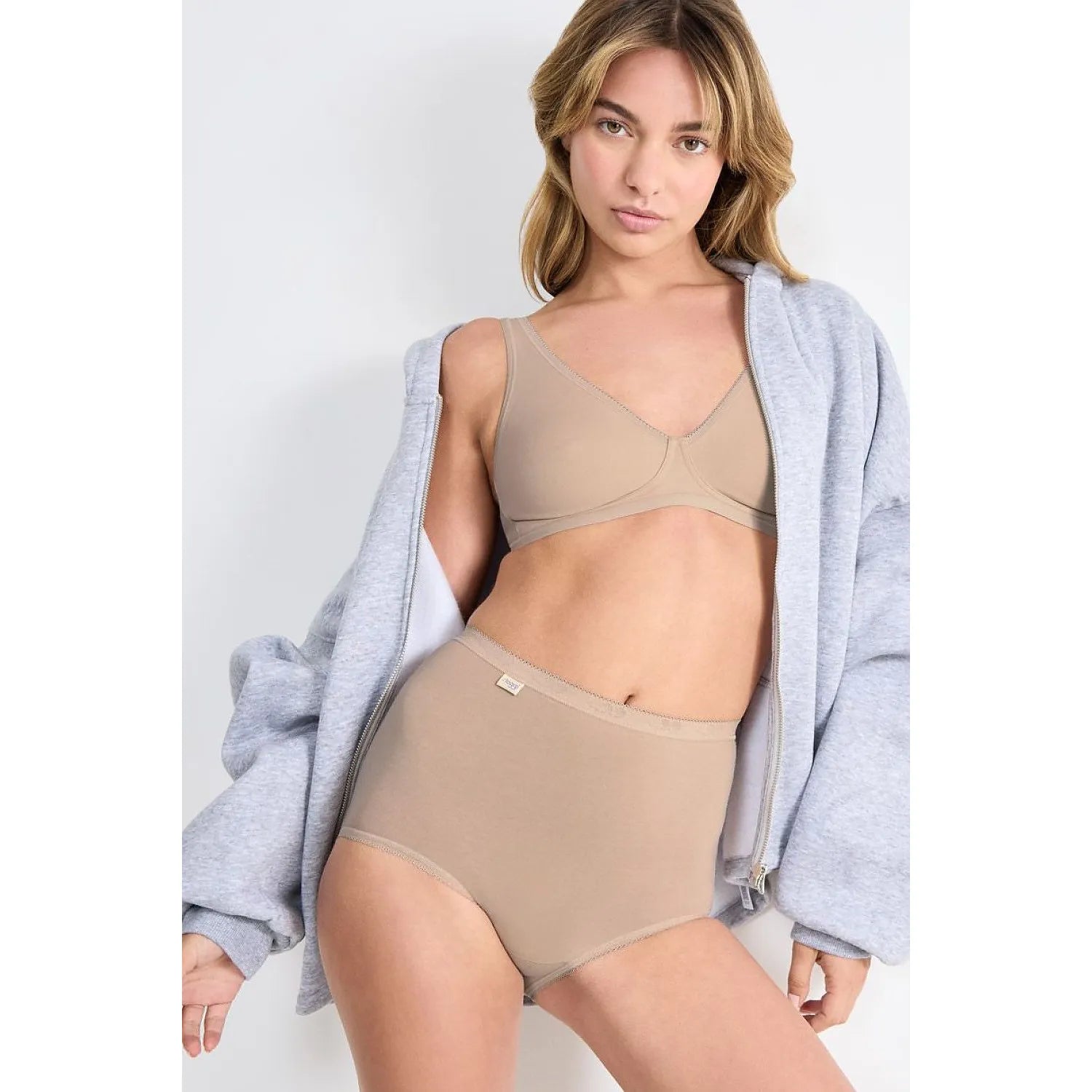Culotte Sloggi Basic+ Maxi beige, coton lycra, ajustement parfait, confort optimal, femme portant une veste grise.