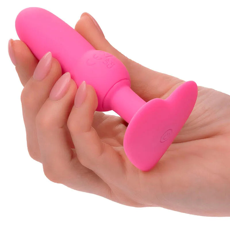 Sonde anale vibrante rose en silicone, forme perlée, tenue en main, avec base large et bouton de commande visible.