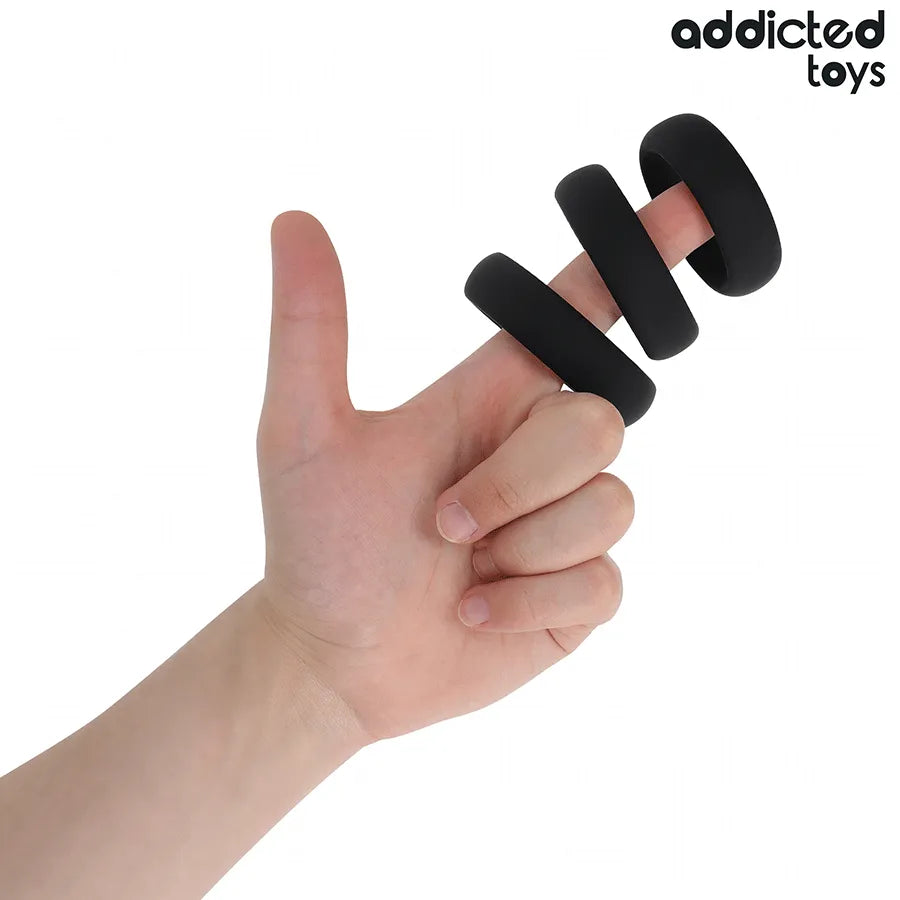 Anneaux péniens plats en silicone noir sur un doigt, design ergonomique pour confort et performance sexuelle optimale.