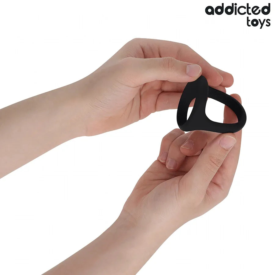 Anneau pénien noir triple épaisseur Addicted Toys, souple et ergonomique, tenu par des mains, améliore performance sexuelle.