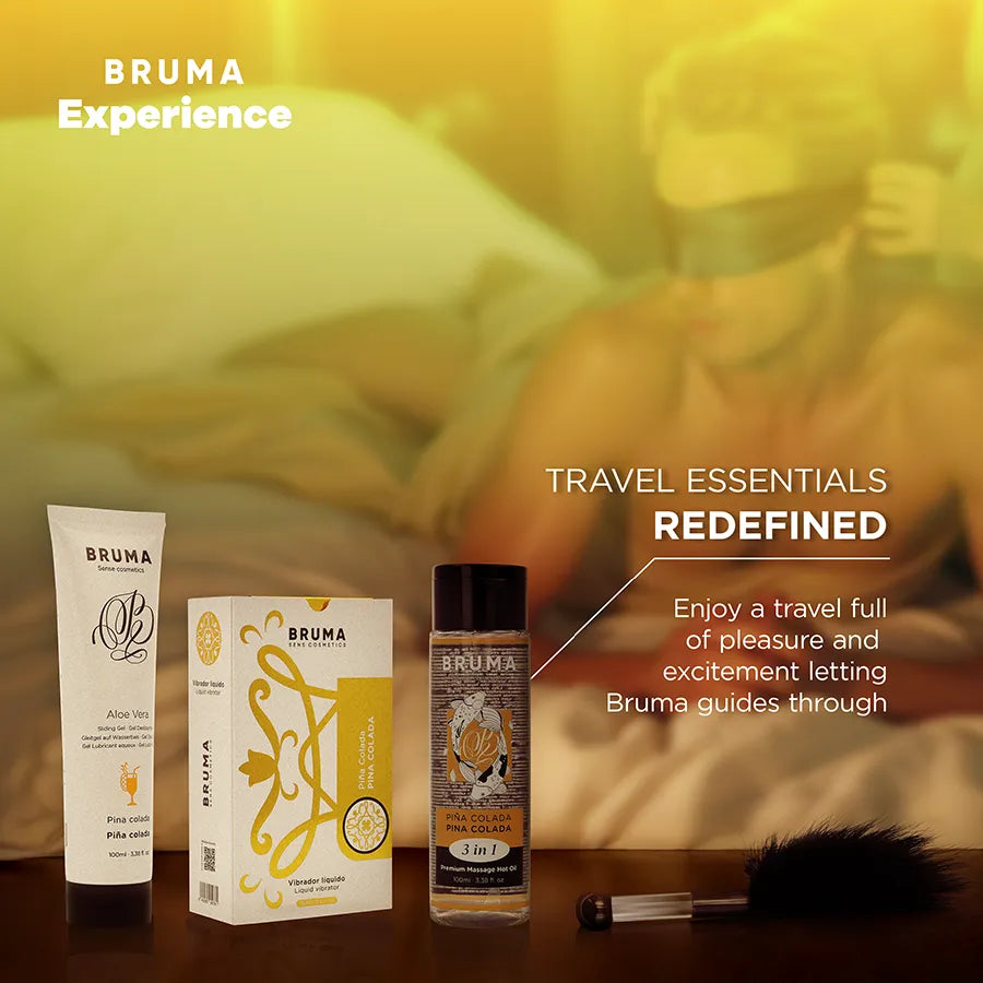 Kit Bruma Xperience avec vibromasseur liquide, lubrifiant, huile, plume noire et bandeau sur fond caribéen.